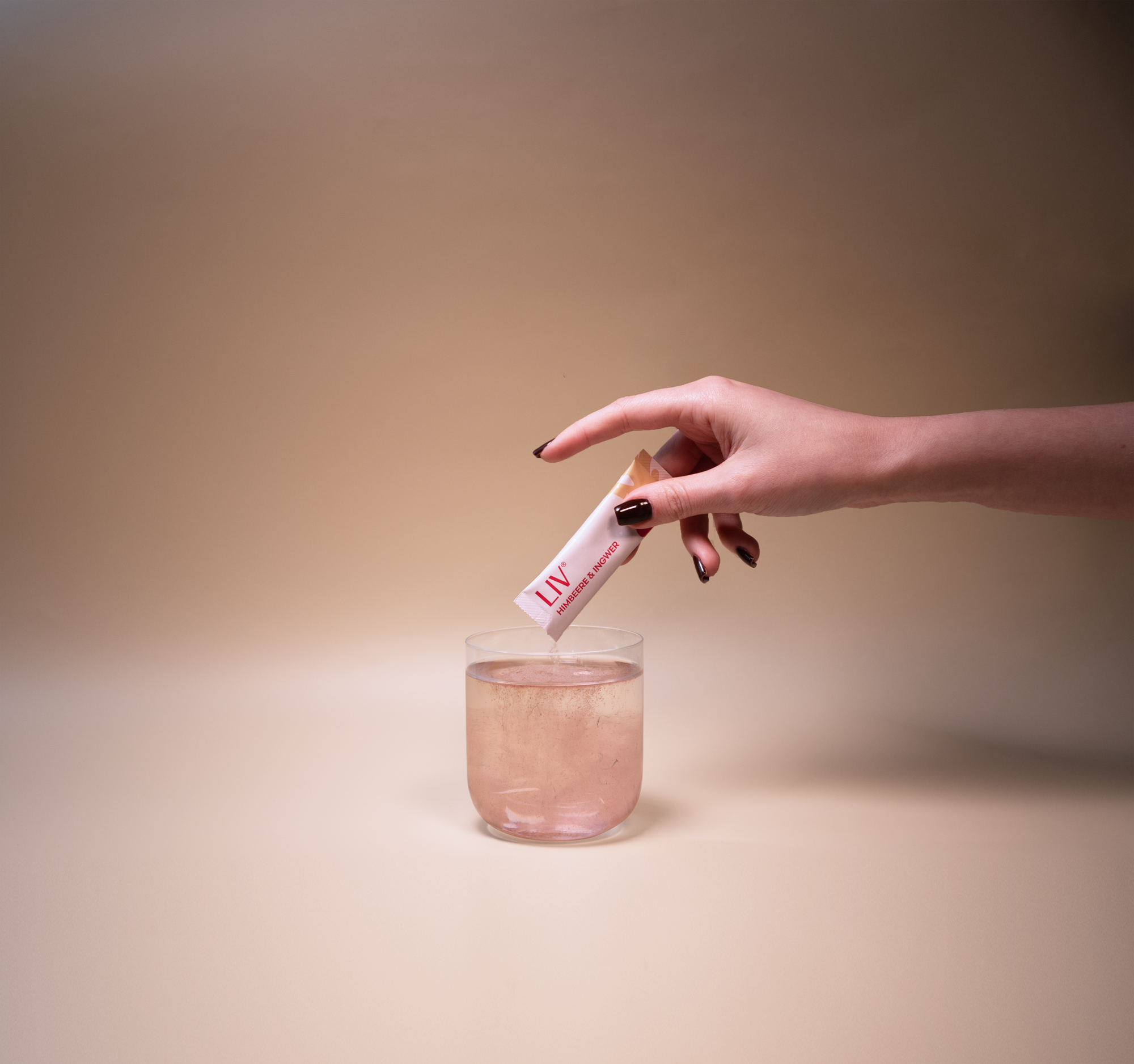 Eine Hand gibt Pulver in ein Glas Wasser.